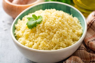 Beton arka planda seramik kase içinde kişniş ile kuskus pişmiş. Seçici odak.