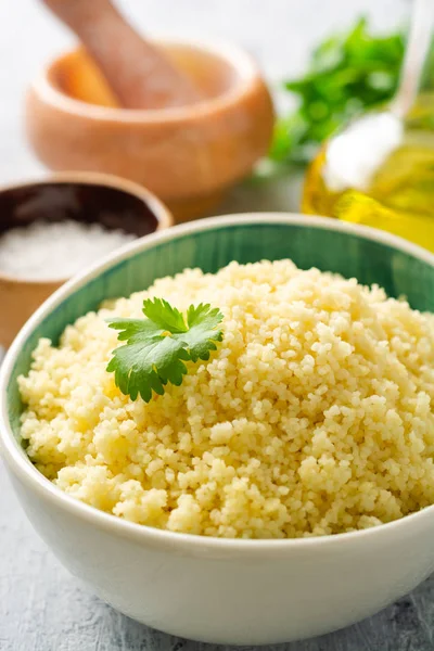 Beton arka planda seramik kase içinde kişniş ile kuskus pişmiş. Seçici odak.