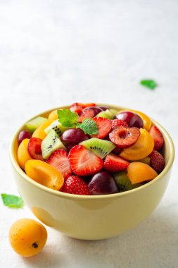 Gri beton arka planda kase sağlıklı taze meyve salatası. Seçici odak.