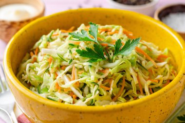 Mor ahşap arka planda kase lahana, havuç ve salatalık ile coleslaw salata. Seçici odak.