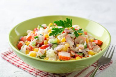 Yengeç çubuklu salata, tatlı mısır, salatalık, haşlanmış yumurta, soğan ve pirinç. Rus mutfağı. Seçici odak.