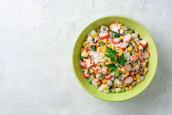 Yengeç çubukları ile salata, tatlı Mısır, salatalık, haşlanmış yumurta, soğan ve pirinç beton arka planda kase. Rus mutfağı. Üst görünüm. Boşluk Kopyala.