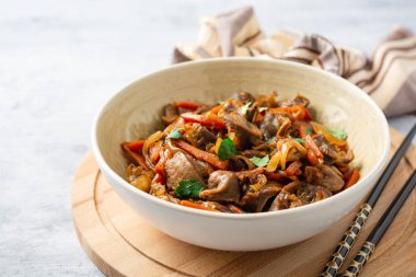 Beton arka planda kase havuç ve soğan ile Fried tavuk taşlığı. Seçici odak.