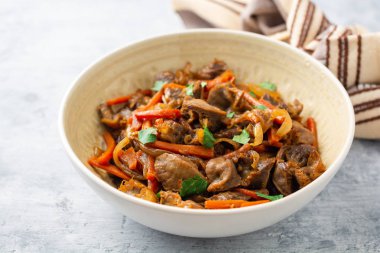 Beton arka planda kase havuç ve soğan ile Fried tavuk taşlığı. Seçici odak.