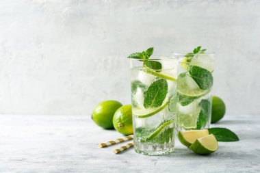 Beton arka planda cam kireç ve nane ile taze Mojito kokteyl. Soğuk serinletici içecek. Seçici odak.