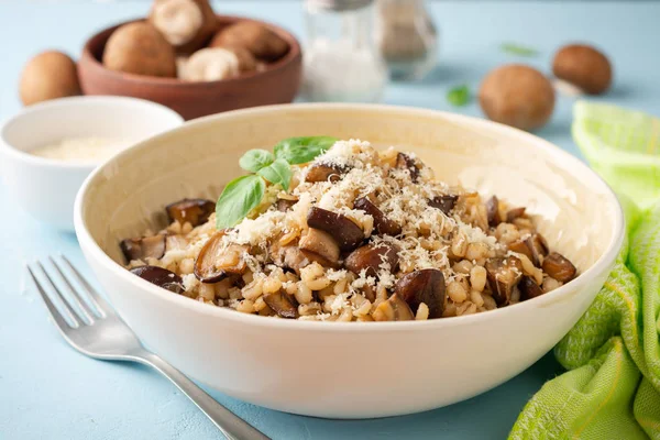 İnci arpa pilavı ya da mantarlı orzotto ve mavi beton arka planda parmesan peyniri. Seçici odak.