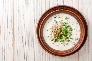 Geleneksel Bulgar soğuk çorba taratörü yoğurt, dereotu, salatalık ve ceviz ile ahşap masada seramik kasede. Üst Manzara. Boşluğu kopyala.
