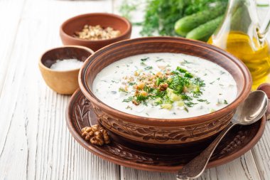 Geleneksel Bulgar soğuk çorba taratörü yoğurt, dereotu, salatalık ve ceviz ile ahşap masada seramik kasede. Seçici odak.