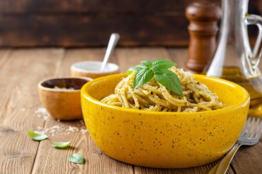 Sosu soslu spagetti makarna ve ahşap masada seramik kasede parmesan peyniri. Seçici odak.