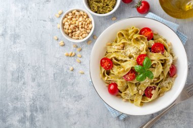 Sos soslu Fettuccine makarna, kiraz domatesleri, çam fıstığı ve çimento arka planda parmesan peyniri. Üst Manzara. Boşluğu kopyala.