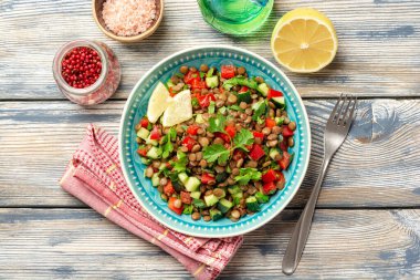 Salatalıklı mercimek salatası, kırmızı biber ve ahşap masa üzerinde kişniş yaprağı. Üst görünüm.