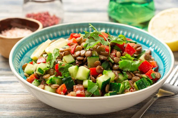 Salatalıklı mercimek salatası, kırmızı biber ve ahşap masa üzerinde kişniş yaprağı. Seçici odak.
