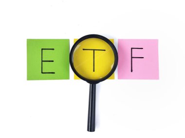 ETF kelimesi beyaz arkaplanda izole edilmiş bir büyüteçle görüntülenen renkli not kağıdına yazılmıştır. Finansal veya yatırım kavramları