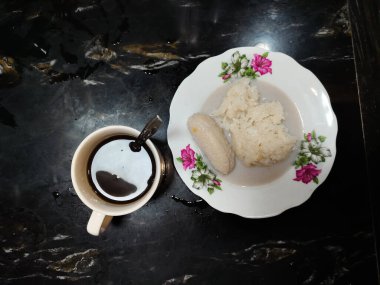 Bir fincan kahve ve hindistan cevizi sütü soslu bir tabak yapışkan pirinç.