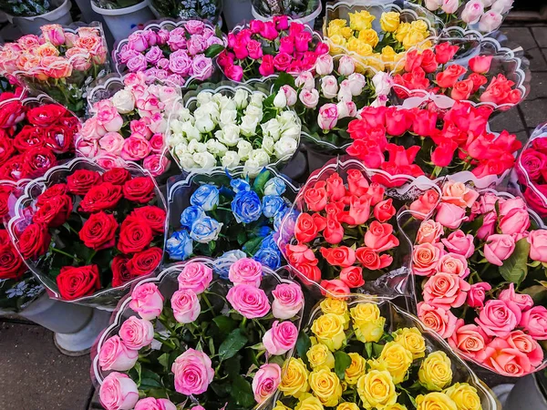 Bouquets of different varieties of roses are sold in the street market. Multi-colored flowers.