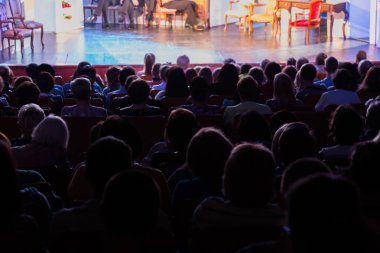 Seyirci bir sinemada bir tiyatro performans, ya da bir konserde. Arkadan ateş. Seyirciler salonda. İnsan siluetleri.