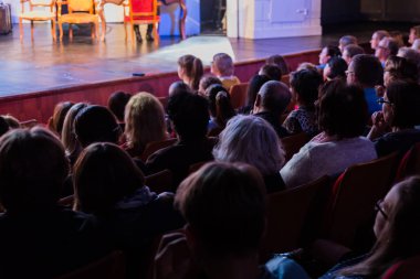 Seyirci bir sinemada bir tiyatro performans, ya da bir konserde. Arkadan ateş. Seyirciler salonda. İnsan siluetleri.