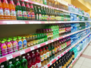 Bulanık soyut resim. Mallar bir bakkal rafta. Çeşitli gazlı içecekler ve cam ve plastik şişe içinde su.