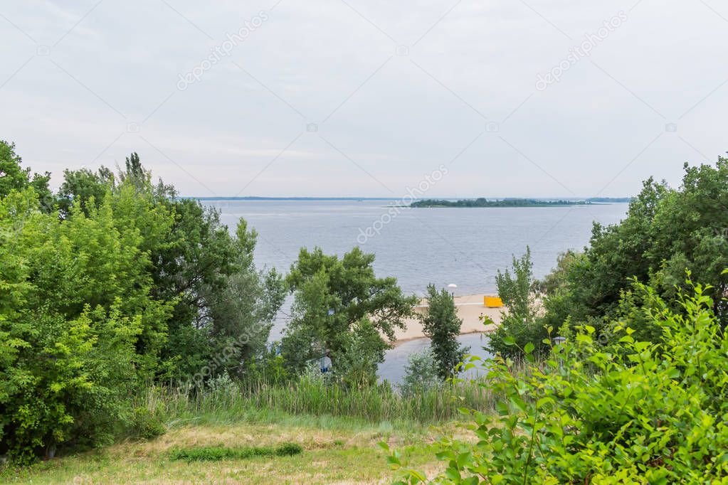 River landscape on a cloudy summer day. Deserted sandy beach.