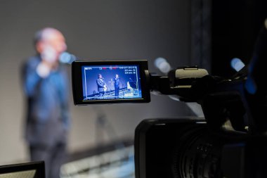 Olayın çekim video. Video kamera Lcd ekran ile. 2 erkek bir gri ekran arka planda mikrofonlar önünde sahnede.