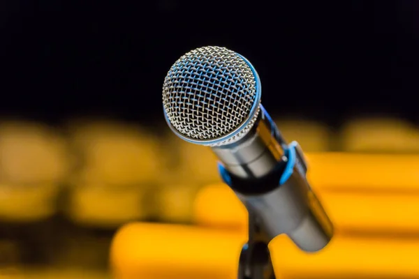 Wireless microphone on stand on blurred background. Empty audience.