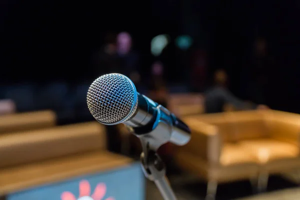 Wireless microphone on stand on blurred background. Unfocused image of people in the background.