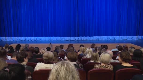 演出前或间歇期在剧院礼堂的人们 舞台上的蓝色窗帘 从后面拍摄 — 图库视频影像
