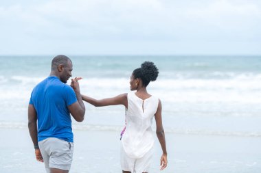 Happy couple enjoying a playful walk on the beach, laughing and holding hands as they splash through the waves together