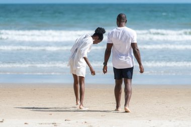 Happy couple enjoying a playful walk on the beach, laughing and holding hands as they splash through the waves together