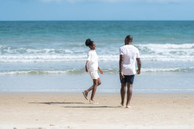 Happy couple enjoying a playful walk on the beach, laughing and holding hands as they splash through the waves together