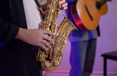 Genç Asyalı grup içeride gitar, klavye, saksafon ve vokalle müzik yapıyor. Yaratıcı grup rahat stüdyo ortamında müzik çalışmasının keyfini çıkarıyor