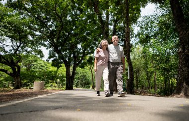 Parkta egzersiz yapan mutlu Asyalı yaşlı çift, dışarıda kaliteli zaman geçirmenin tadını çıkarıyor.