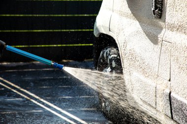 Basınçlı yıkama makinesi olan bir arabaya uygulanan beyaz köpük temizlik, bakım ve modern araba yıkama teknolojisinin canlı bir görüntüsünü oluşturur (araba yıkama serisinin bir parçası).).