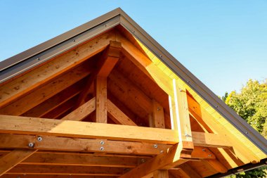 Güneş ışığı, güzel inşa edilmiş bir ahşap çatı iskeletinin içinden nazikçe süzülür, açıkta kalan kirişler ve güçlü civatalar doğal ahşabın zengin buğdayını vurgular..