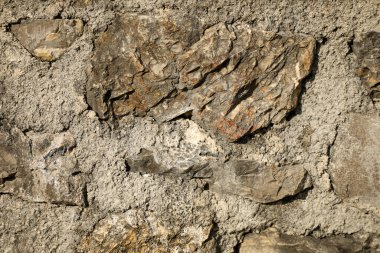 Beton harca döşenmiş doğal kayaların yer aldığı sert taş duvarın yakın plan ayrıntıları, dokuyu ve maddi kontrastı vurguluyor.