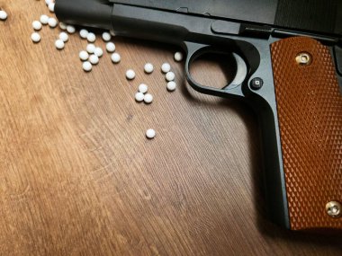 Close-up image of a black semi-automatic pistol on a wooden surface. Though just an airsoft replica, the photo showcases the weapon's beauty, evoking power and danger.