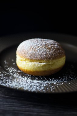 Kahverengi bir plaka üzerinde taze ev donute ile pudra şekeri serpilir.