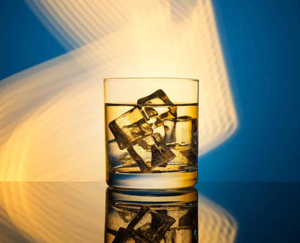 Ein Glas Mit Einem Getränk Und Eiswürfeln Auf Blauem Hintergrund — Stockfoto