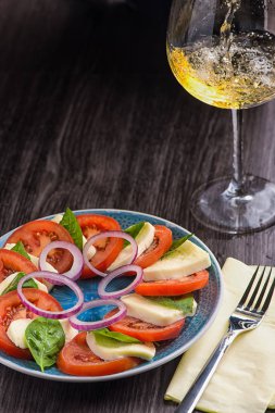 Süs karanlık bir tablo içinde bir restoran ile mavi tabakta Caprese salatası.