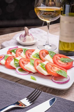 Bir restoranda masa lambası üzerinde bir süsleme ile mavi tabakta Caprese salatası.