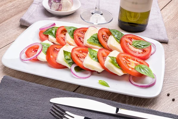 Bir restoranda masa lambası üzerinde bir süsleme ile mavi tabakta Caprese salatası.