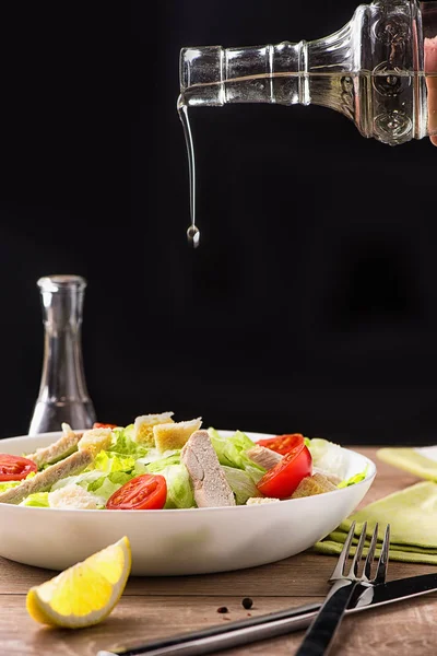 Sezar Salata tavuk doğal masa lambası ve çatal bıçak takımı ile siyah arka plan ile.