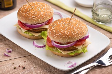 Hamburger çift peynir, kırmızı soğan ve domates beyaz dikdörtgen plaka restoran parlak bir tablo ile.