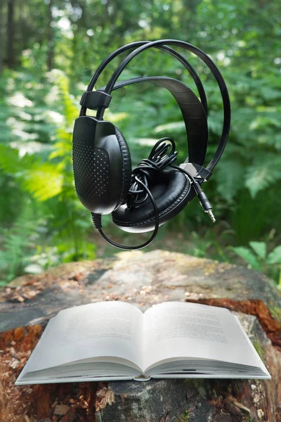 Μαύρα Ακουστικά Και Ένα Λευκό Βιβλίο Στο Δάσος Ένα Κούτσουρο — Φωτογραφία Αρχείου