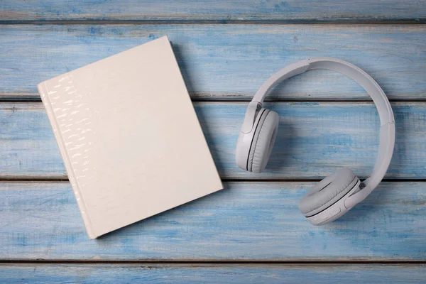 Λευκά Ακουστικά Και Ένα Λευκό Βιβλίο Για Μπλε Και Μπεζ — Φωτογραφία Αρχείου