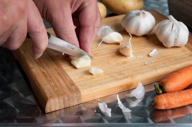 Tahta bir tahtanın üzerinde sarımsak soymak ve kesmek. Erkek eli..