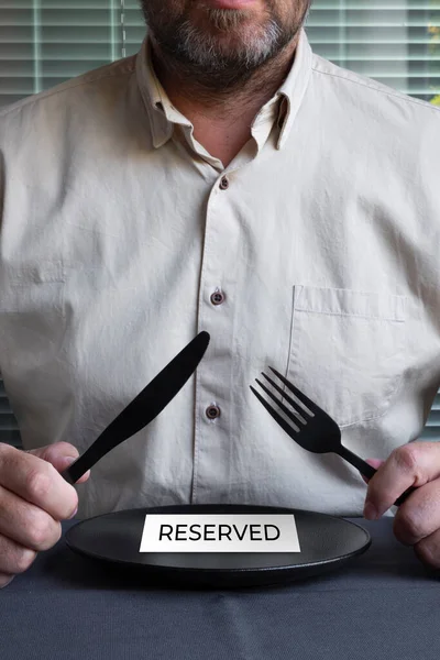 Homem Camisa Bege Numa Mesa Com Prato Preto Vazio Garfo — Fotografia de Stock