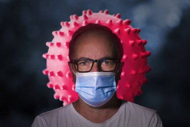 Beyaz tişörtlü bir doktor, mavi yüzlü bir adam, covid-19 virüsünün arasında.
