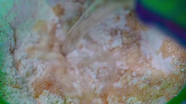 Close-up of a person using a hand to mix flour and liquid in a bowl, preparing dough for home baking. High quality 4k footage
