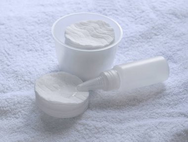 Pamuklu hijyenik ped, bir arka plan beyaz terry havlu karşı küçük şişe. 